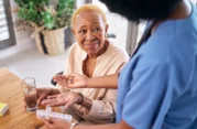 elderly woman gets pills from a health care worker