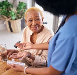 elderly woman gets pills from a health care worker