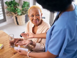 elderly woman gets pills from a health care worker