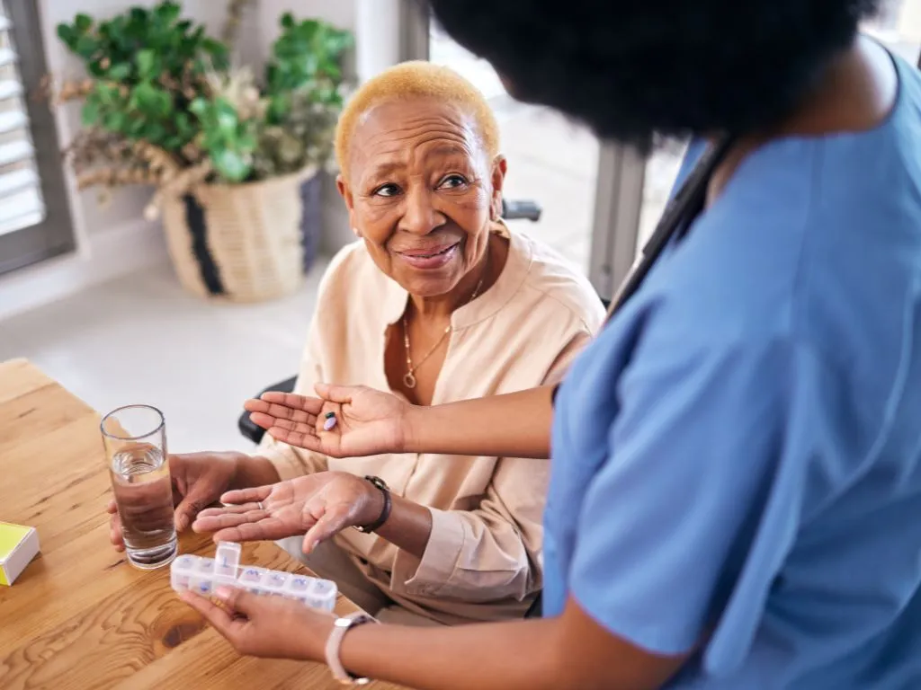 elderly woman gets pills from a health care worker