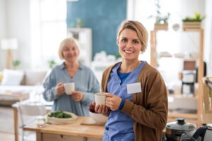 Caregiver smiling with senior woman at home during daily care support