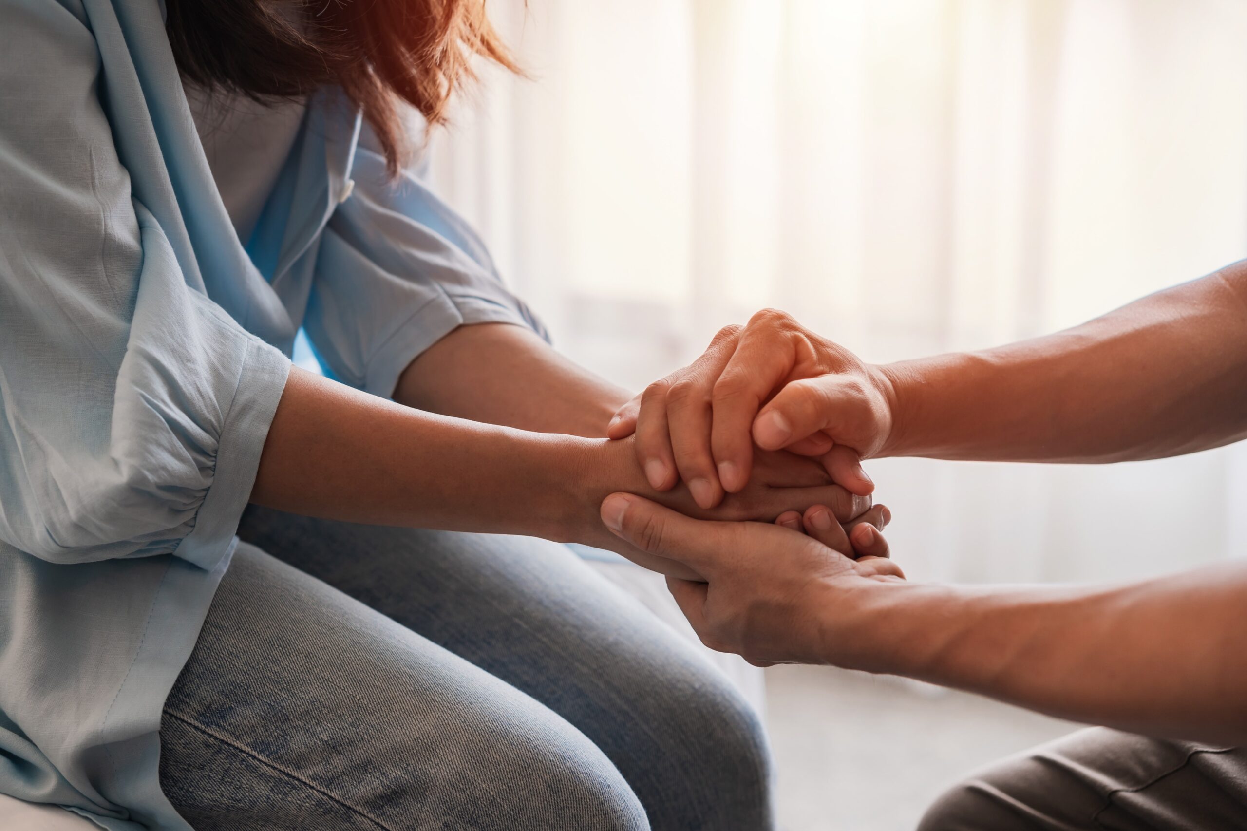 Close-up of caregiver holding hands to comfort a person in need