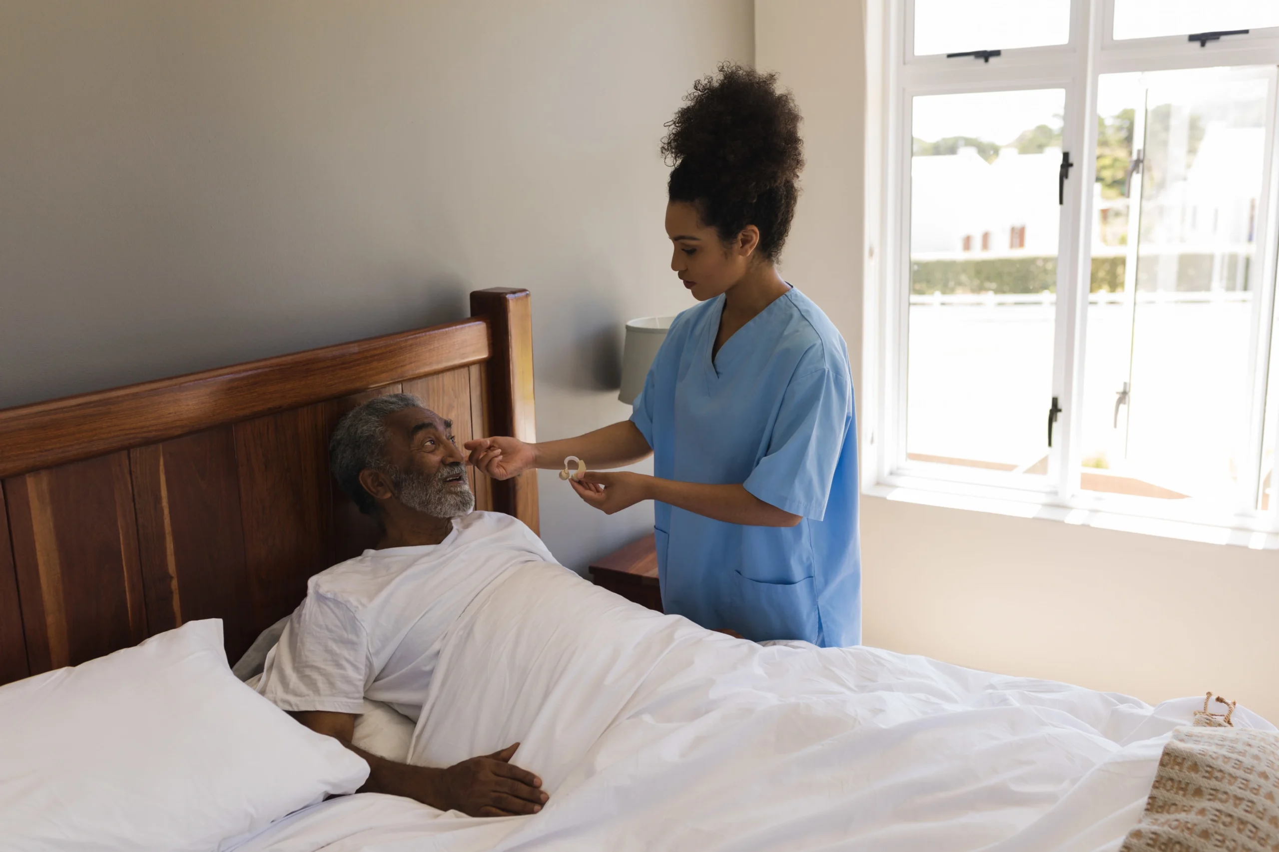 Professional home care nurse assisting an elderly man in bed, ensuring comfort, safety, and improved quality of life.